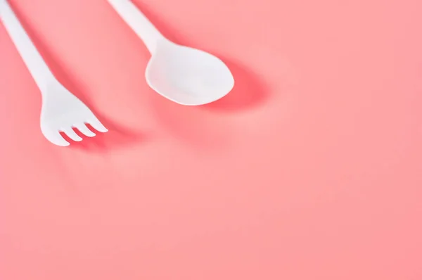 粉红背景上的白色即弃勺子和叉子 拯救环境 野餐娱乐 派对和其他活动的概念 复制空间 — 图库照片