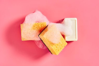 Pembe arka planda süngerin yanında köpük köpüklü sabun kalıbı. Yıkama, temizlik kavramı