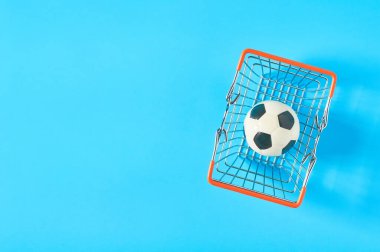 Futbol, futbol, mavi arka planda metal market sepeti. Spor aksesuarları alıyorum. Sporda yolsuzluk kavramı