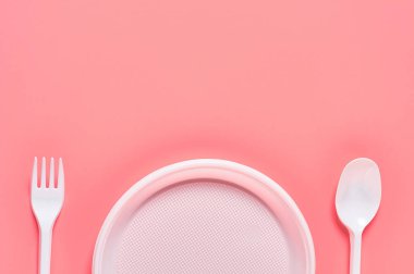 Pembe arka plana saçılmış tek kullanımlık plastik kaplar. Çevreyi, ekolojiyi, piknik, parti ve diğer etkinlikleri kurtarma kavramı. Uzayı kopyala Üst görünüm
