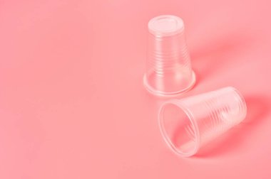Pembe arka plana saçılmış tek kullanımlık plastik bardaklar. Çevreyi, ekolojiyi, piknik, parti ve diğer etkinlikleri kurtarma kavramı. Boşluğu kopyala