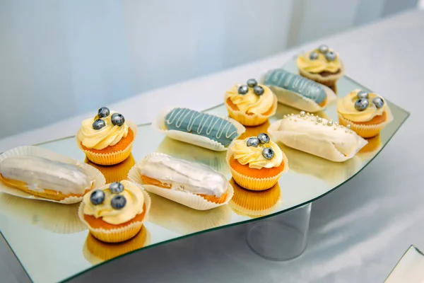 Small cakes, cupcakes, eclairs, close-up. Sweets on unusual plate, interesting presentation. Restaurant service, anniversary, wedding.