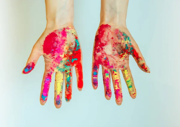 Concept of Holi, Indian festival of colors. Image of women's hands on white background, close-up. Powdered paints on palms.
