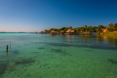Laguna de Bacalar, Meksika 'nın Bacalar şehrinde bulunan Yedi Renk Gölü olarak da bilinir. Kristal berrak sular ve gölün beyaz kumlu tabanı su renginin gün boyunca değişen turkuaz, mavi ve derin çivit renklerine dönüşmesine neden olur.