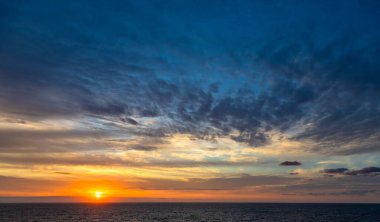 Karayip Denizi 'nin tropikal sularında sürüklenen günbatımı ve dramatik bulut kümeleri gün ışığının son anlarıyla aydınlanır..