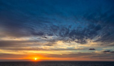 Karayip Denizi 'nin tropikal sularında sürüklenen günbatımı ve dramatik bulut kümeleri gün ışığının son anlarıyla aydınlanır..
