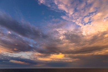 Karayip Denizi 'nin tropikal sularında sürüklenen günbatımı ve dramatik bulut kümeleri gün ışığının son anlarıyla aydınlanır..