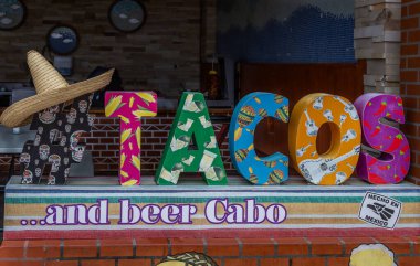 Cabo San Lucas, Meksika 'da Tacos ve Bira Cabo kelimelerini taşıyan renkli bir kurul.