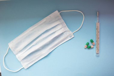 Virüs önleme ve tedavi: maske takmak, el dezenfeksiyonu, antiviral ilaçlar ve vitaminler. Mavi arka planda ilaçları olan ilk yardım çantası..