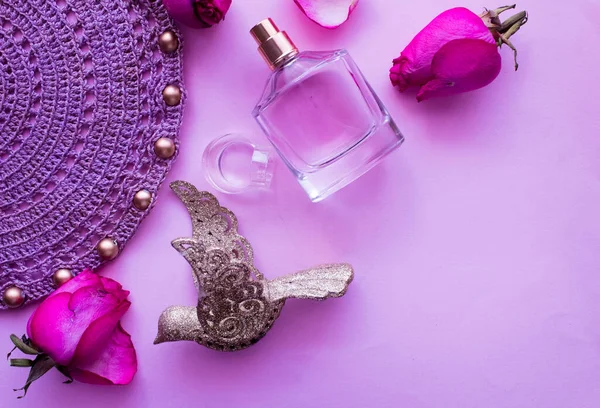 Perfume rosa brotes y pétalos de rosa sobre un fondo rosa, servilleta de punto con cuentas — Foto de Stock