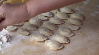 Mutfaktaki kadın masada hamur işi yapmayı öğretiyor.