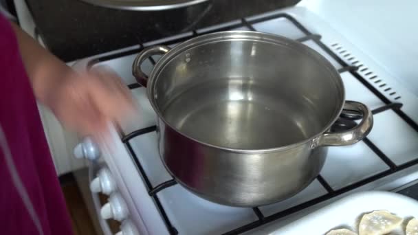 Mulher na cozinha perto de um fogão a gás em uma panela de bolinhos para cozinhar — Vídeo de Stock