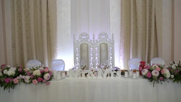 Twee bruidsstoelen aan de huwelijkstafel. de tafel is versierd met bloemen. Mr Mrs Huwelijksteken op bruid en bruidegom tafel. — Stockvideo