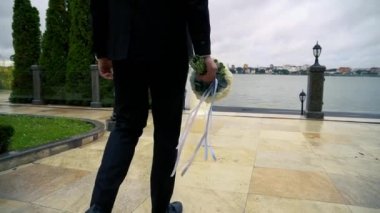 Elinde buket olan bir adam geline gider.