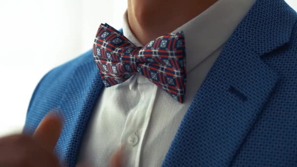 A man in a blue jacket and white shirt corrects blue and red bow tie. — Stock Video
