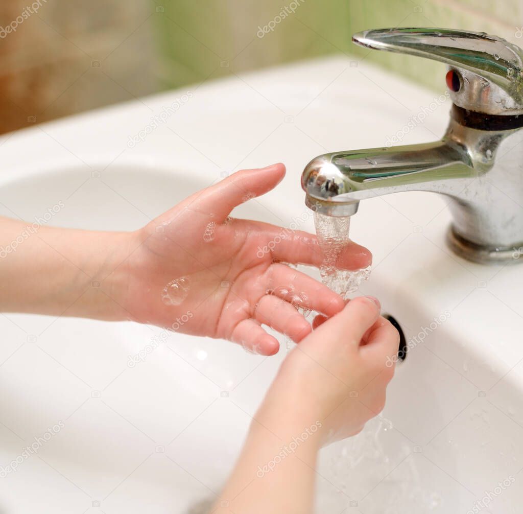 Child during washing hands in bathroom. Mandatory hygiene rule. Close up of hands