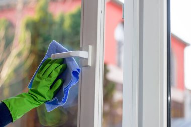 Açık plastik pencerenin temizlenmesi. Koruyucu eldiven ve temizleme bezi.