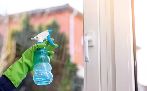 Cleaning of closed vinyl plastic window. Protective glove on hand and cleaning sprinkle