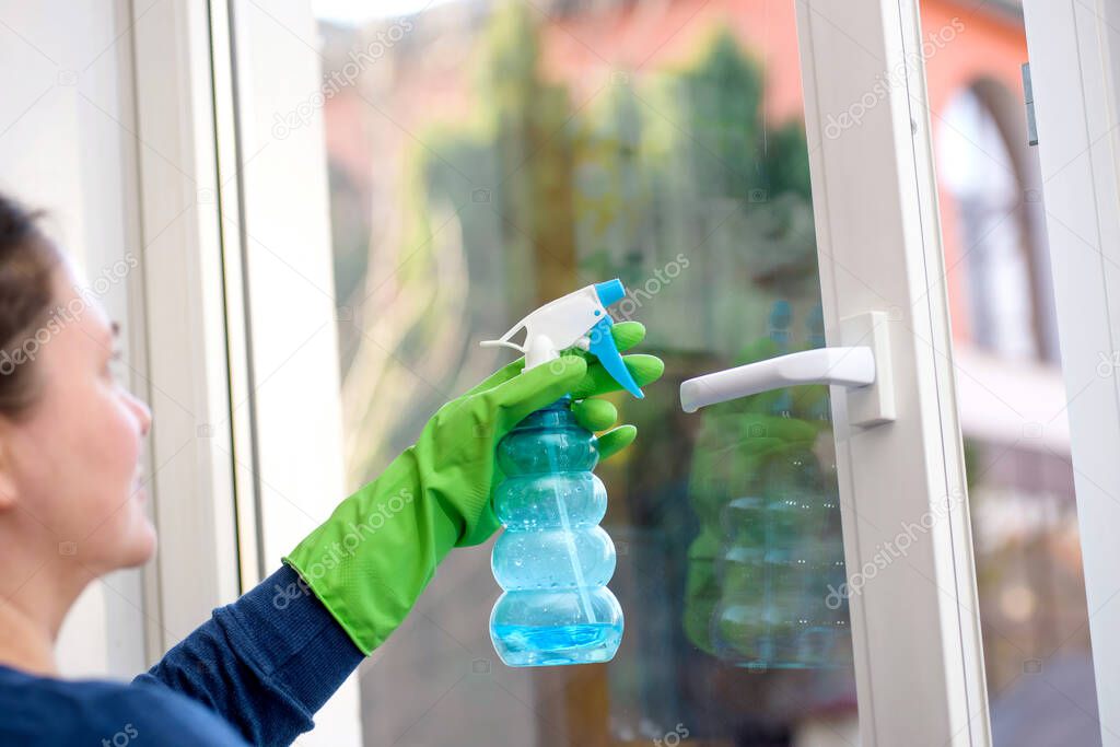 Cleaning of opened vinyl plastic window. Protective glove on hand and cleaning sprinkle
