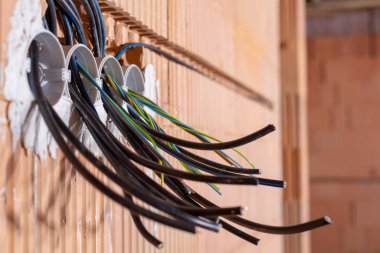 Duvarda kablolar olan kutular. Kablo arka plan. Duvardaki elektrik prizlerinden sarkan renkli elektrik kabloları. Yeni elektrik kablosu kurulumu.