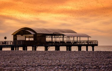 Gün batımında deniz kıyısındaki iskelede bir restoran.