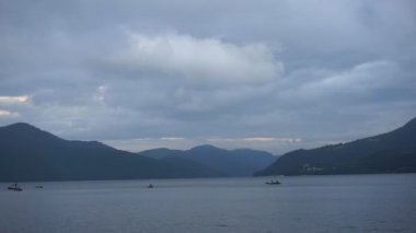 Dusk uzaktan balıkçı tekneleri ile dağ gölü etrafında bizimkiler yaşar