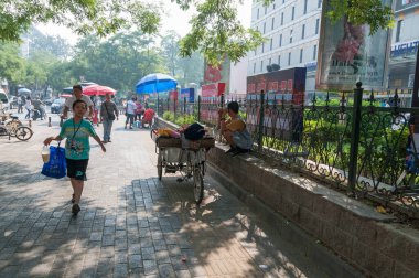 Bir kişi triportör bisikletinden meyve satıyor ve insanlar yürüyor.