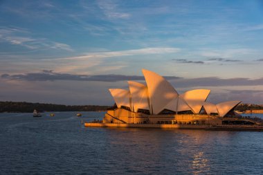 Günbatımında Sydney Opera Binası. Arkasında renkli gökyüzü var.