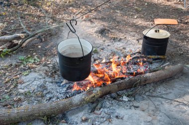 Kamp ateşinin tepesinde asılı haşlanmış çorbayla.