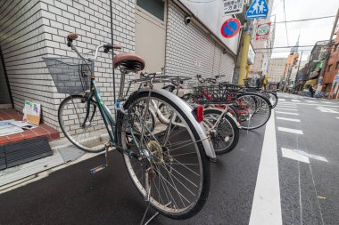 Yol kenarına Japon sokak işaretleri olan bisikletler park etmiş. 