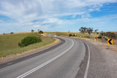 Avustralya kırsalında asfalt yol. Dönek yolu olan kırsal altyapı manzarası