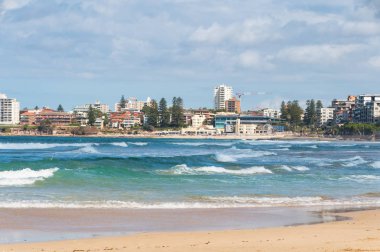 Beautiful beach with mild waves and cityscape on the background
