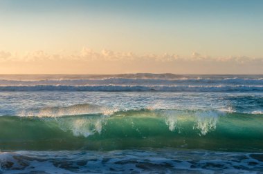 Turquoise blue transparent ocean wave at sunrise