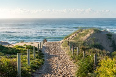 Entrance path to ocean beach with sand with many footsteps