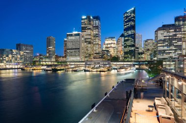 Geceleri aydınlatılmış ofis binalarıyla Sydney şehri manzarası