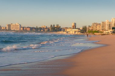 Tanınmayan sörfçü ve şehir manzaralı gündoğumu sahili deniz manzarası 