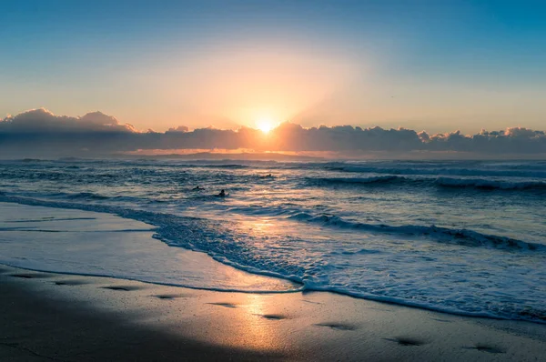 Espectacular paisaje marino al amanecer con surfistas irreconocibles en el — Foto de Stock
