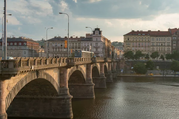 Трамвай движется по старому мосту через реку Влтаву в Праге — стоковое фото