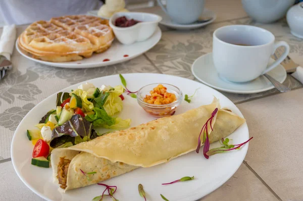 Breakfast, light meal table setting with crepe wrap, salad and B
