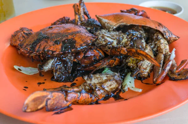 Close up of black pepper crab served on bright orange plate — ストック写真