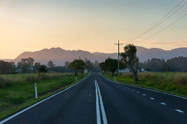 Countryside landscape with asphalt road and mountains on the bac — Stock Photo, Image