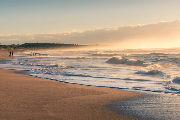 Playa del océano al amanecer con gente irreconocible haciendo deportes — Foto de Stock