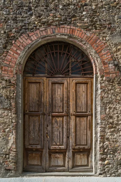 Arch doorway with old wooden door and stone wall — 스톡 사진