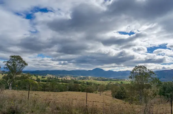 Paysage rural avec champs de paddock et montagnes lointaines, collines — Photo