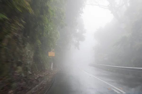 Estrada de montanha ventosa no nevoeiro. Condições de condução perigosas metaforos — Fotografia de Stock