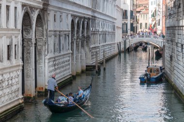 Venetian canal with tourists in traditional Venetian gondola