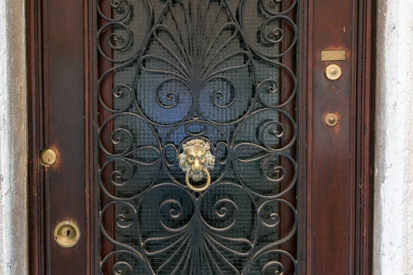 Closed wooden door with cast iron frame and metal door knocker — 스톡 사진