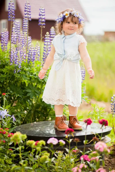 Счастливая девочка с цветочным венком в саду — стоковое фото