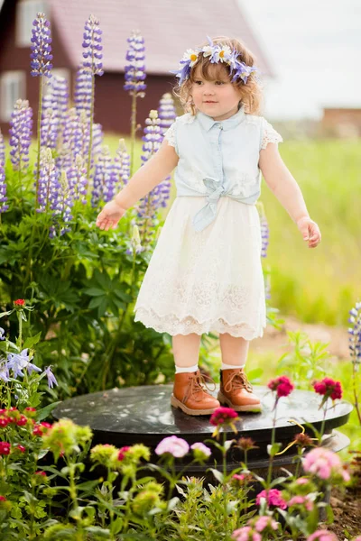 Heureuse jeune fille avec une couronne de fleurs dans le jardin — Photo