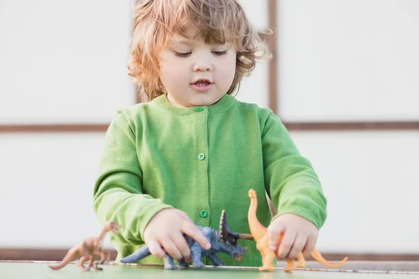 Kleinkind spielt mit einem Spielzeug-Dinosaurier — Stockfoto